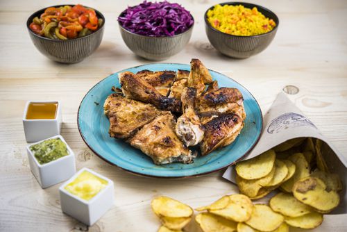 Pollo servido con guarniciones, salsas y patatas.
