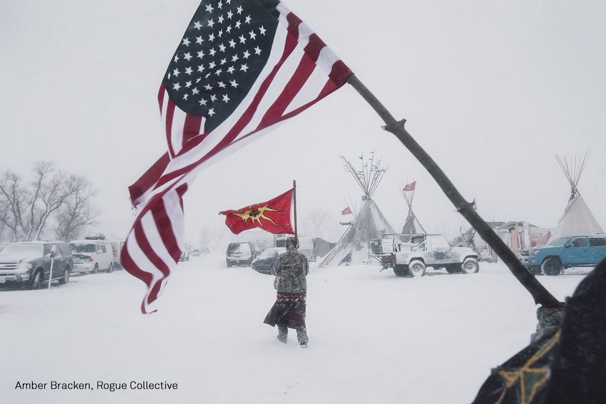 La gente porta una bandera americana y una Sociedad Mohawk Warrior en un campo de protesta contra el Dakota Access Pipeline, en Cannon Ball, Dakota del Norte, Estados Unidos.