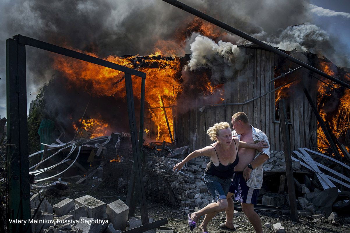 Los civiles escapan de un incendio en una casa golpeada durante un ataque aéreo, en la aldea de Luhanskaya, Luhansk, en julio de 2014.