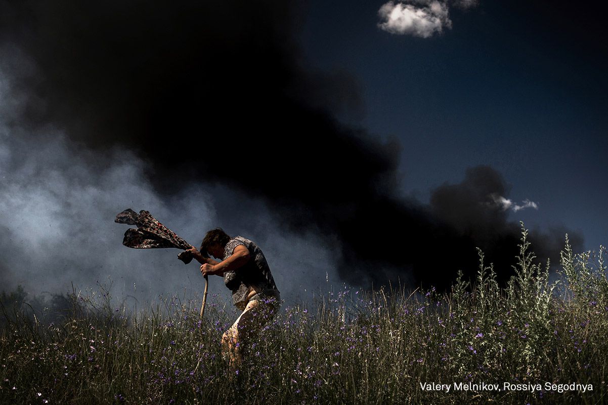 Una mujer escapa de un incendio durante un ataque de artillería en la carretera Krasnodon, en Luhansk.