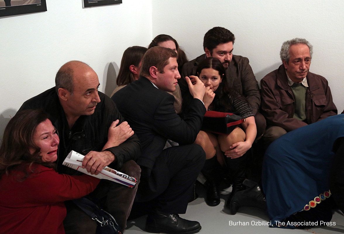 La gente se agacha en un rincón de una galería de arte en Ankara, después del asesinato del embajador ruso.