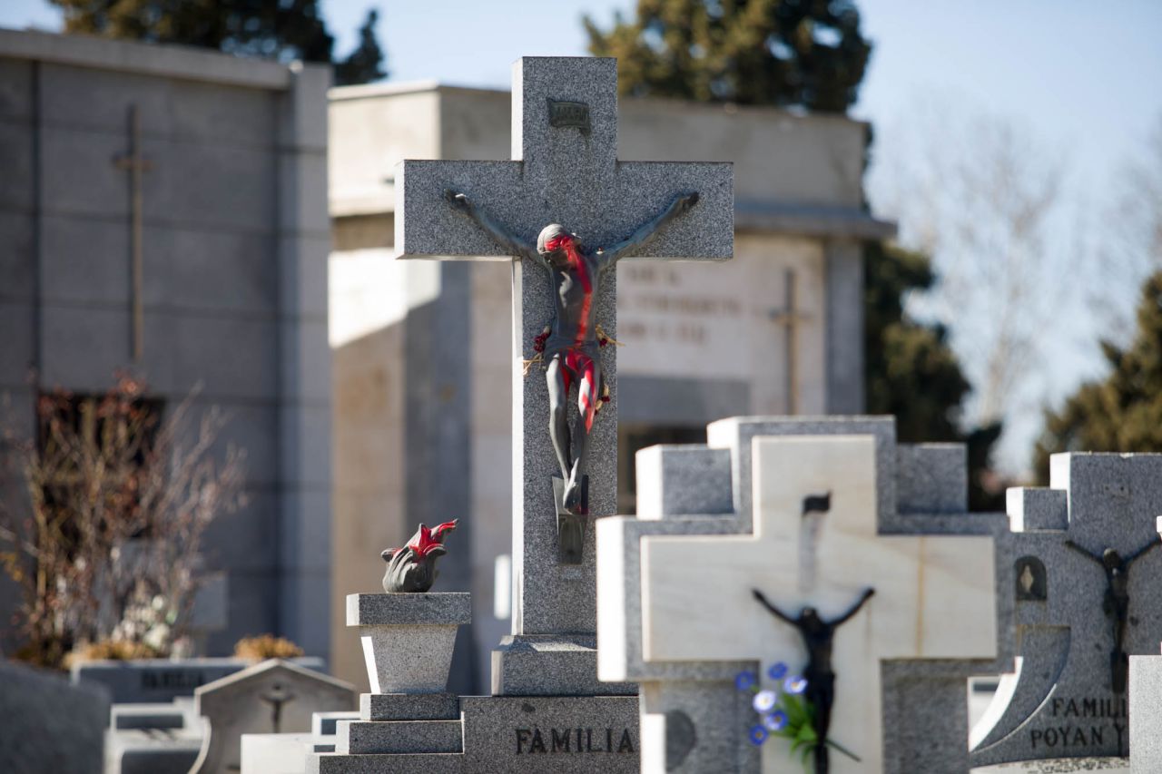 Un Cristo en una tumba pintado con spary rojo en actos vandálicos.