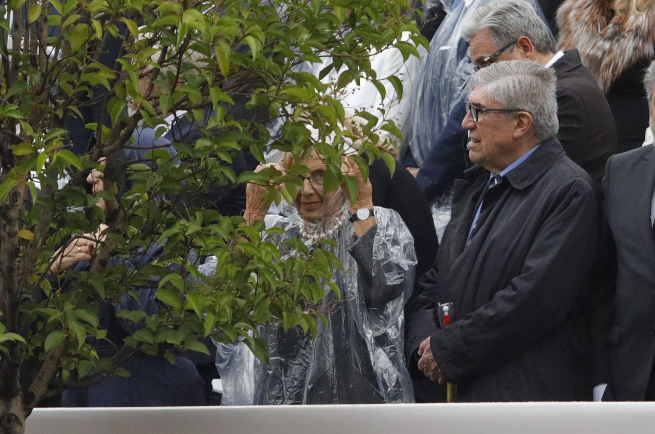 Manuela Carmena, en la tribuna de personalidades, protegiéndose de la lluvia.