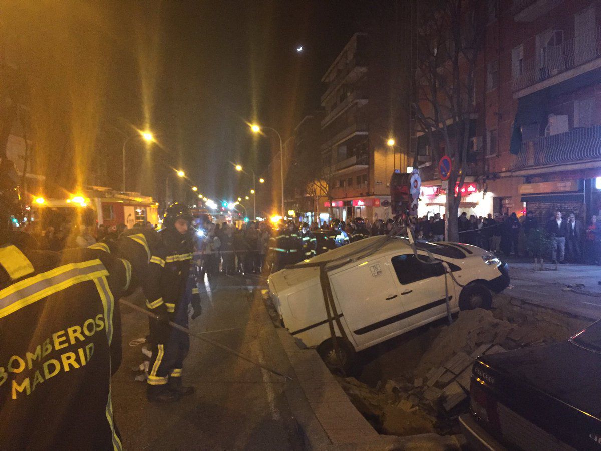 Los Bomberos sacan los dos turismos atrapados en el socavón de Ciudad Lineal con la ayuda de una grúa. 
