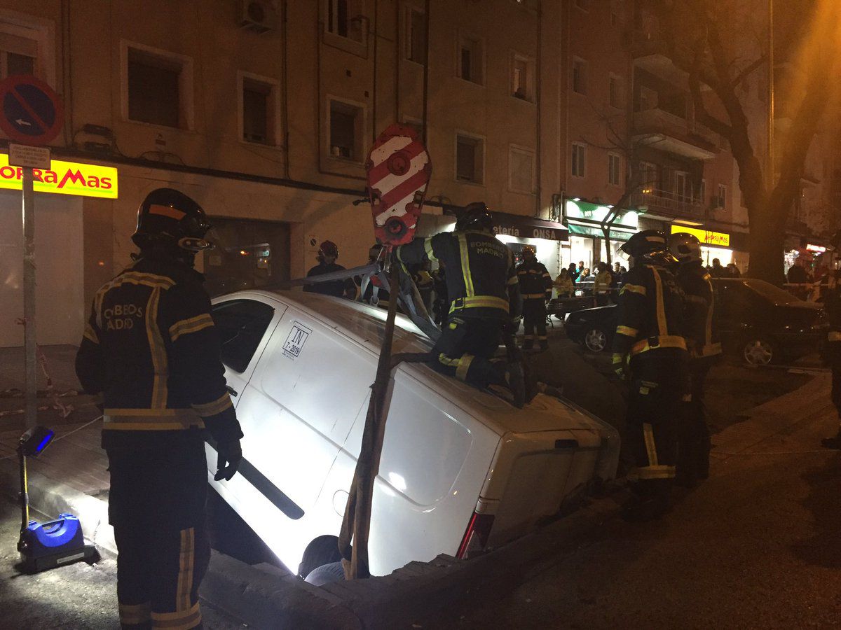 Los Bomberos sacan los dos turismos atrapados en el socavón de Ciudad Lineal con la ayuda de una grúa. 