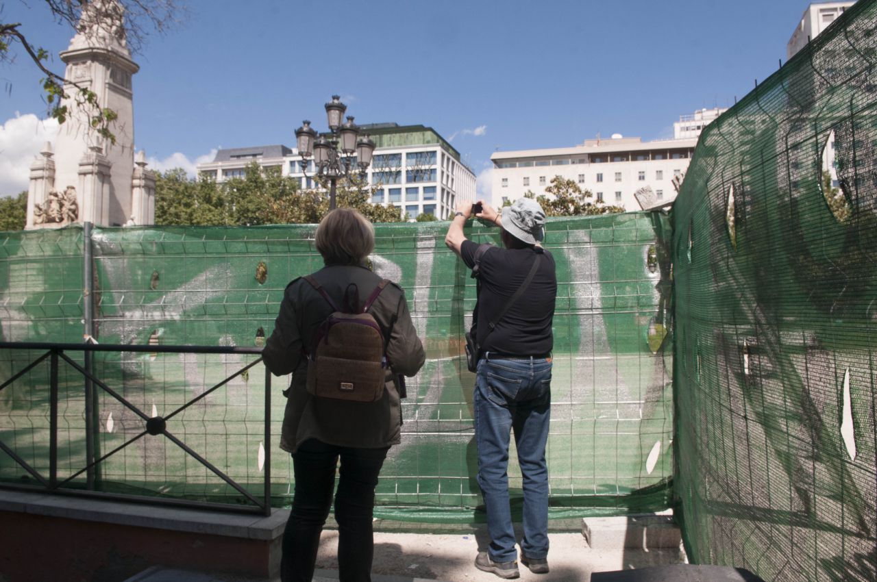 Los turistas intentan fotografiar la Plaza de España, aunque sea por encima de las vallas.