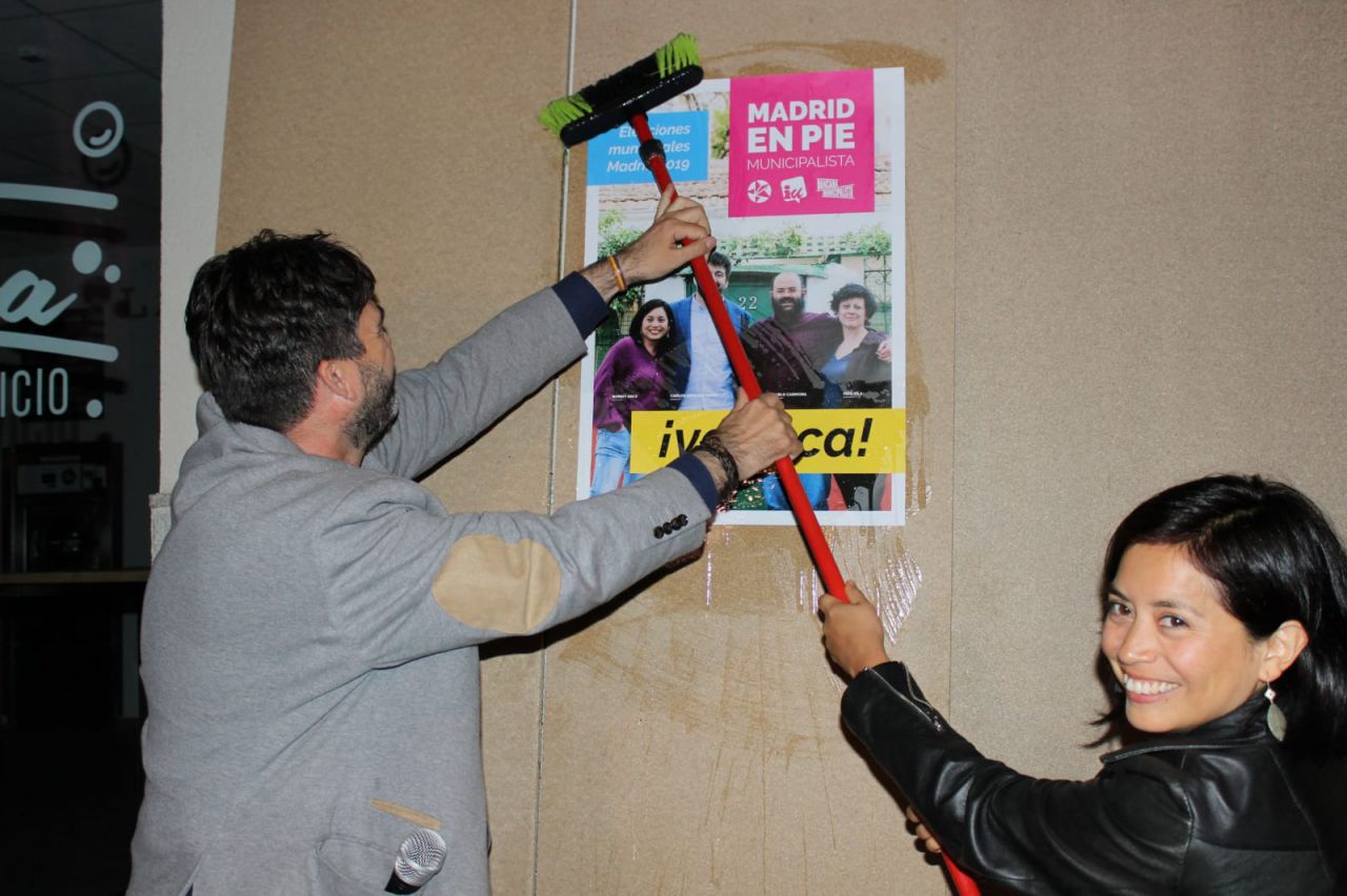 Carlos Sánchez Mato y Rommy Arce pegando uno de los carteles.