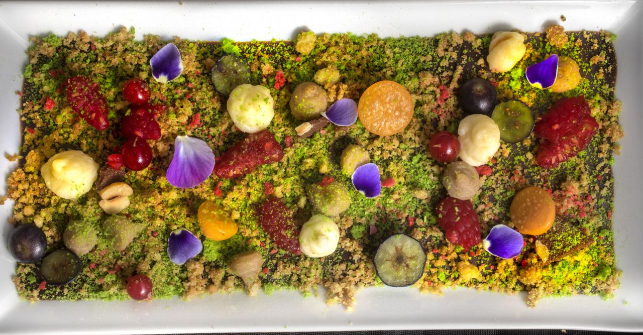  El jardín del chef un plato que nos traslada al panel central de la obra más misteriosa del Bosco: El Tríptico del jardín de las delicias. Los frutos rojos, los pétalos y el chocolate en diferentes texturas, evocan el escenario natural y los placeres efímeros que disfrutan los personajes que habitan este enigmático jardín.