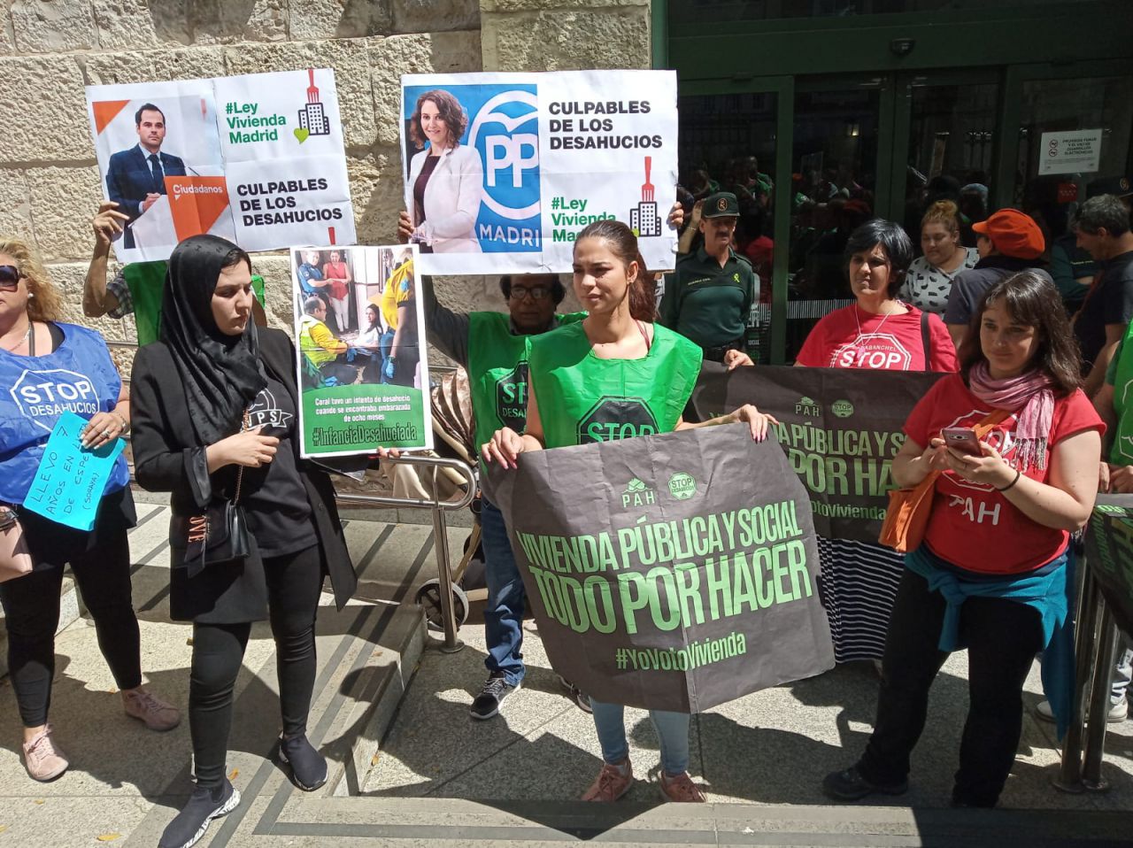 Distintas personas protestan en la Consejería de Vivienda con diversas pancartas.