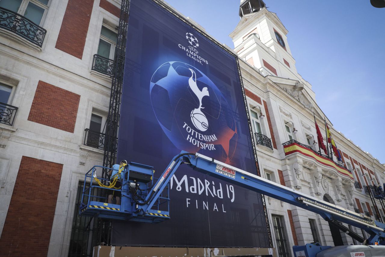 De la fachada de la Casa de Correos cuelgan dos lonas con los escudos del Liverpool y el Tottenham. 