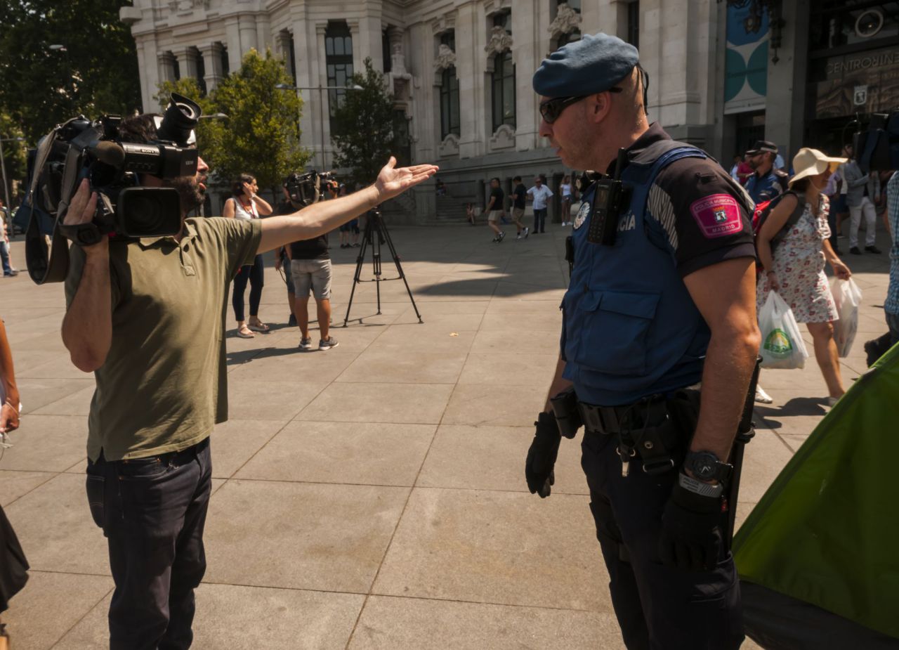 Un cámara de televisión frente a uno de los agentes que han participado en el desalojo. 