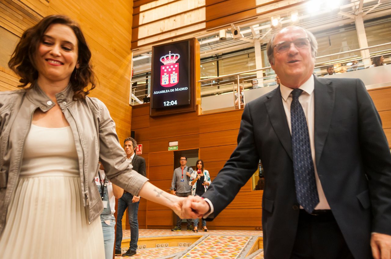 Isabel Díaz Ayuso, candidata de PP, coge de la mano a Ángel Gabilondo, candidato del PSOE, tras el pleno de constitución de la Asamblea de Madrid