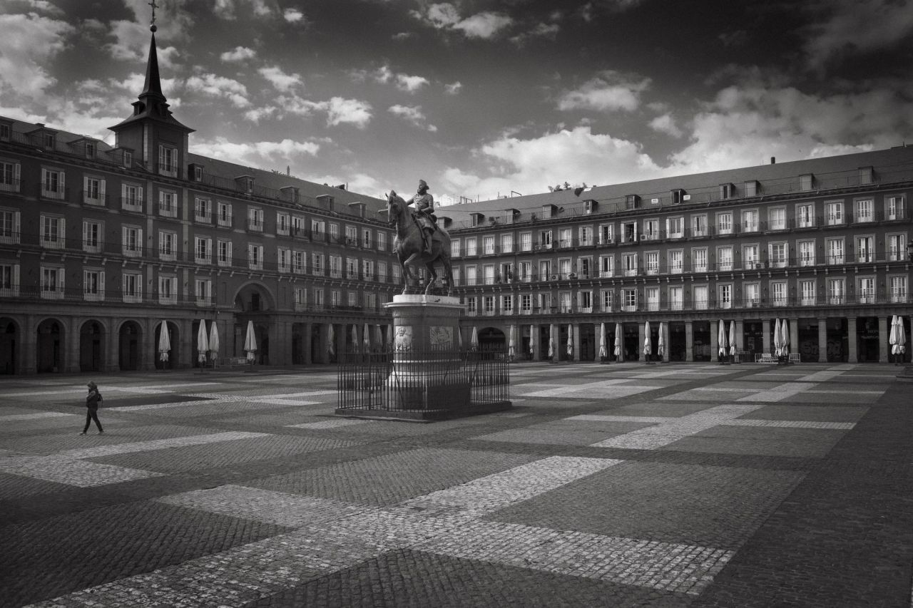 Una persona cruza la solitaria Plaza Mayor de Madrid el primer día del confinamiento. Las sombrillas recogidas son el único recuerdo de las bulliciosas terrazas.