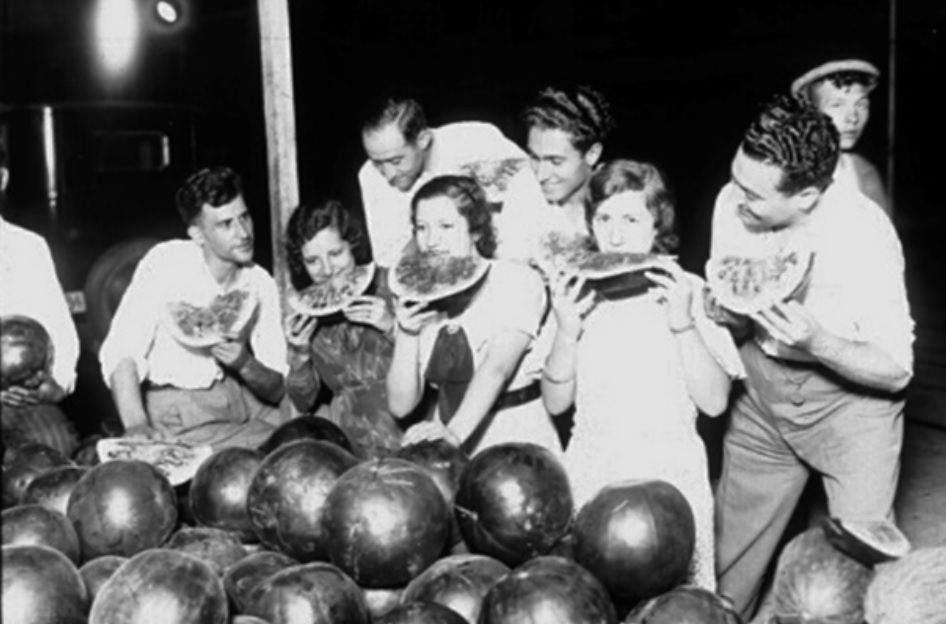 1935. Un grupo de jóvenes degusta una gran sandía en un puesto de la calle.
