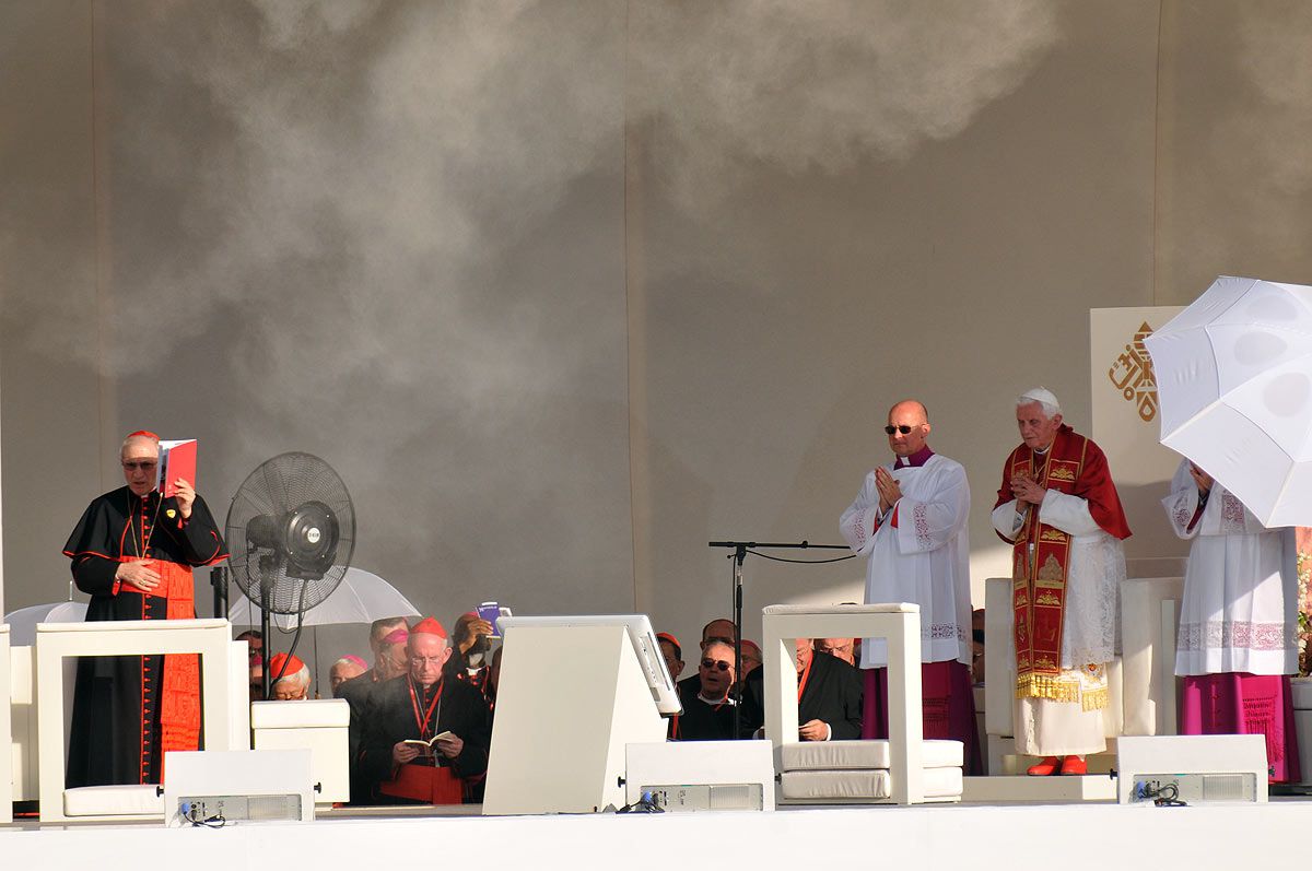 El Papa Benedicto XVI rodeado de fieles y obispos en Cibeles durante las Jornada Mundial de la Juventud y a un lado -tapándose con un libro del sol- el cardenal Rouco Varela.