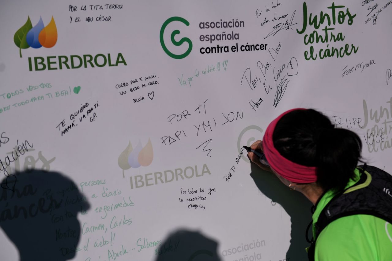 Varias personas dejan mensajes en un mural durante la celebración de la X Carrera Madrid en marcha por el Cáncer, en el Paseo de la Castellana.
