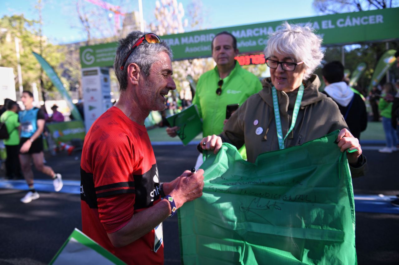 El campeón del mundo de maratón 1995, Martín Fiz, firma una bandera durante la celebración de la X Carrera Madrid en marcha por el Cáncer.