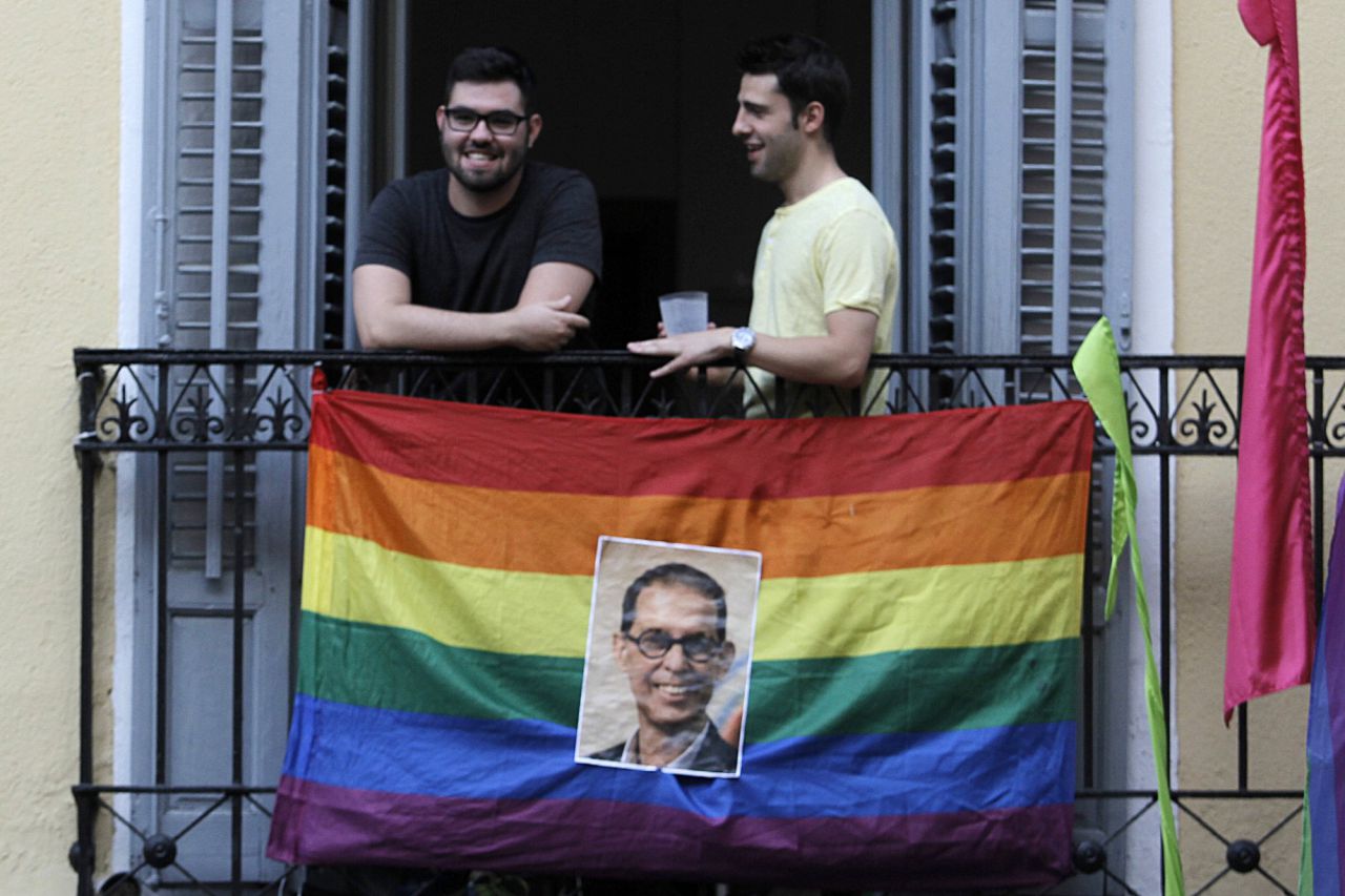 Una foto de Pedro Zerolo decora una bandera arcoiris en un balcón de la pza de Chueca.