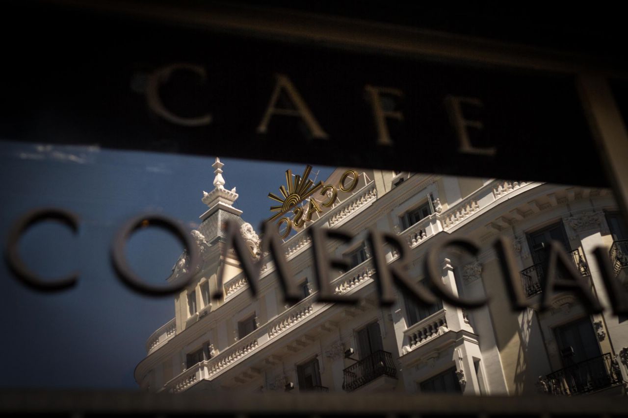 Reflejo del edificio de la aseguradora Ocaso en el cartel del Café Comercial.
