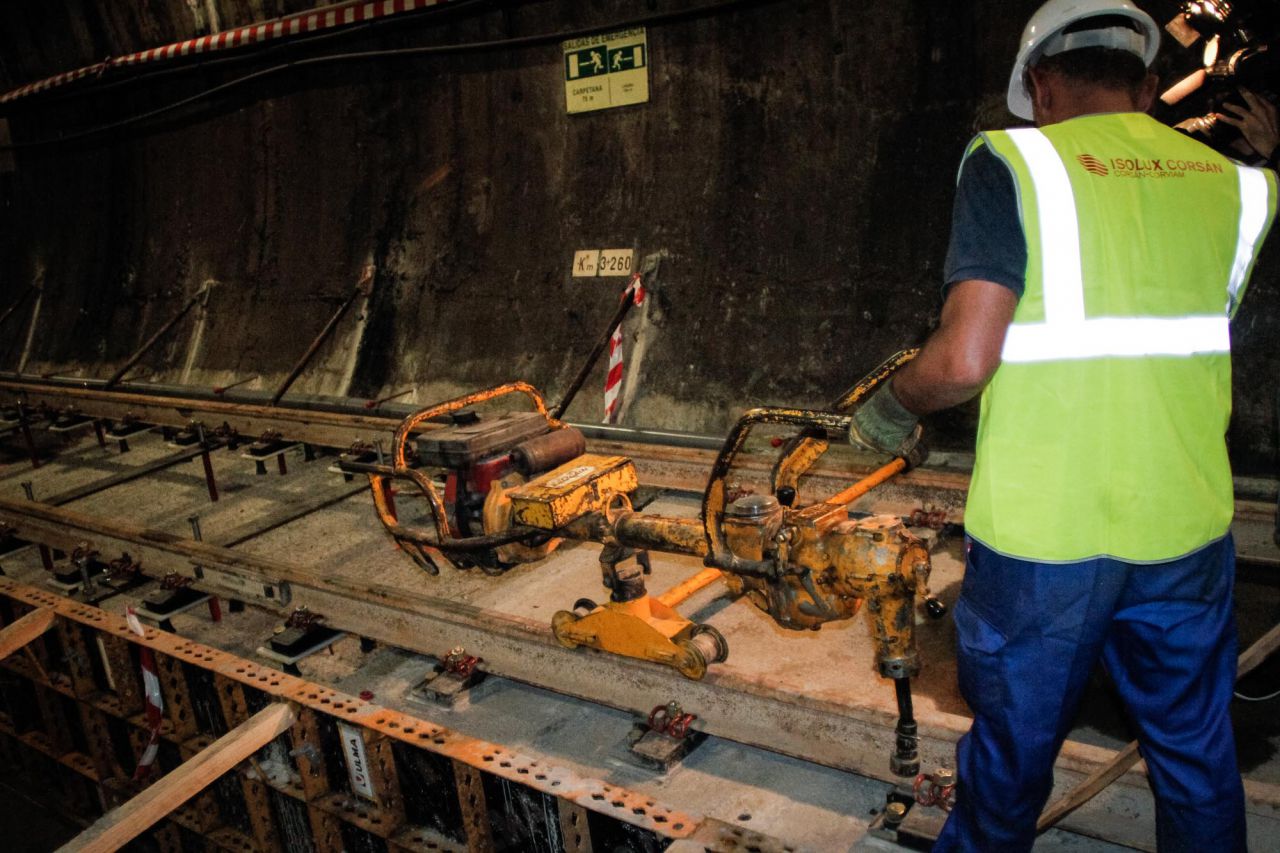 Un trabajador aprieta las tuercas que sujetan las vías de metro en la estación de Carpetana.