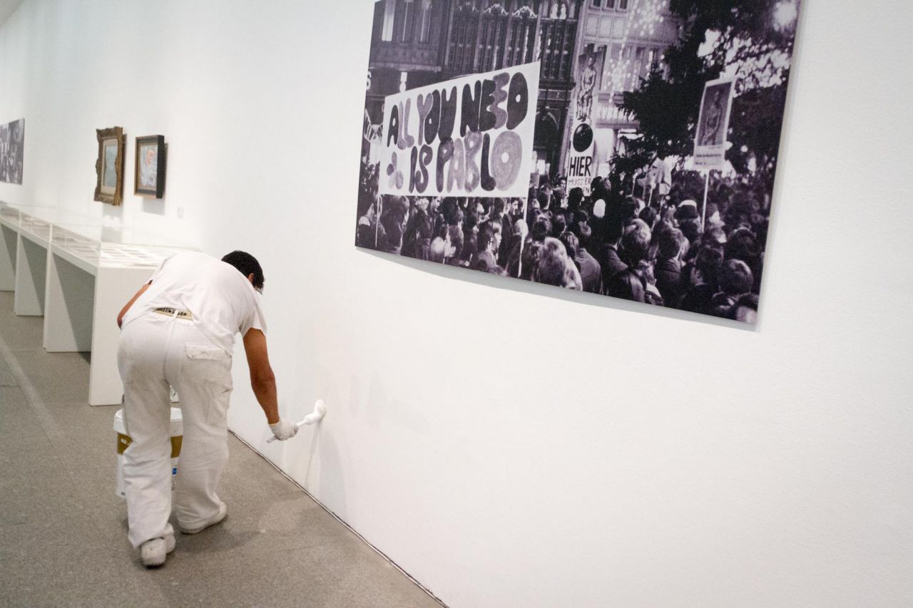 Un operario de mantenimiento repasa con pintura rozaduras en la pared de una de las salas de exposición.
