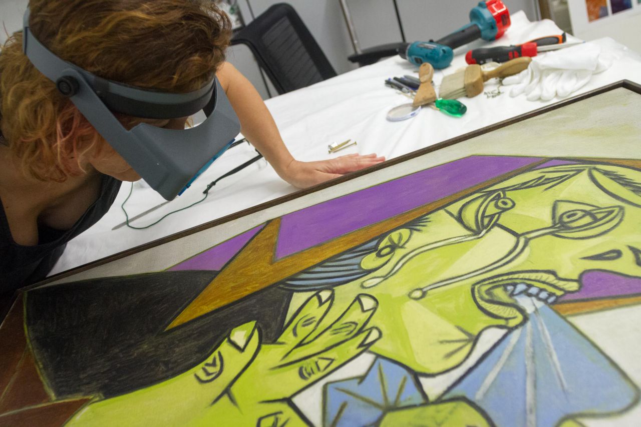 Una restauradora observa con gafas de aumento los trazos de un cuadro de Picasso en el taller de restauración.