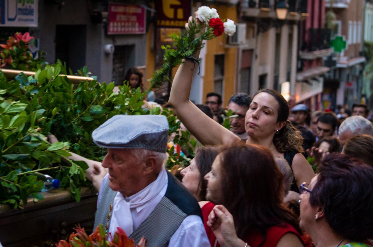 La gente se agolpa al finalizar el recorrido para coger las flores a los pies del santo.