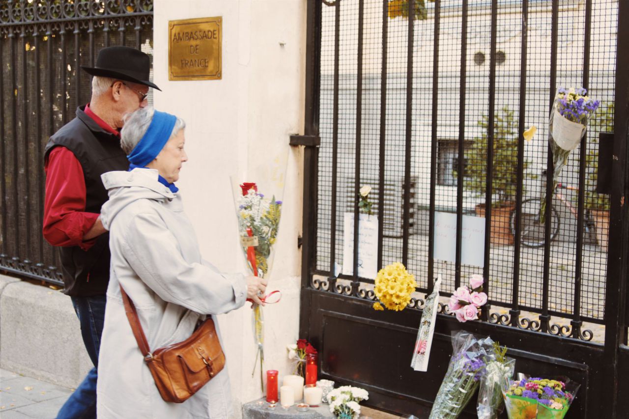 Señores dejando flores en la puerta de la Embajada de Francia en Madrid.