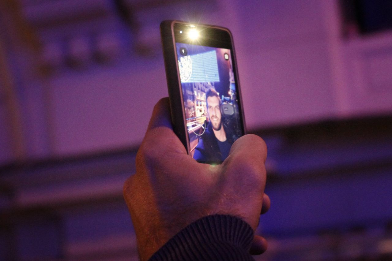 Un cámara de televisión se hace un doble selfie iluminado por las luces de la Gran Vía.