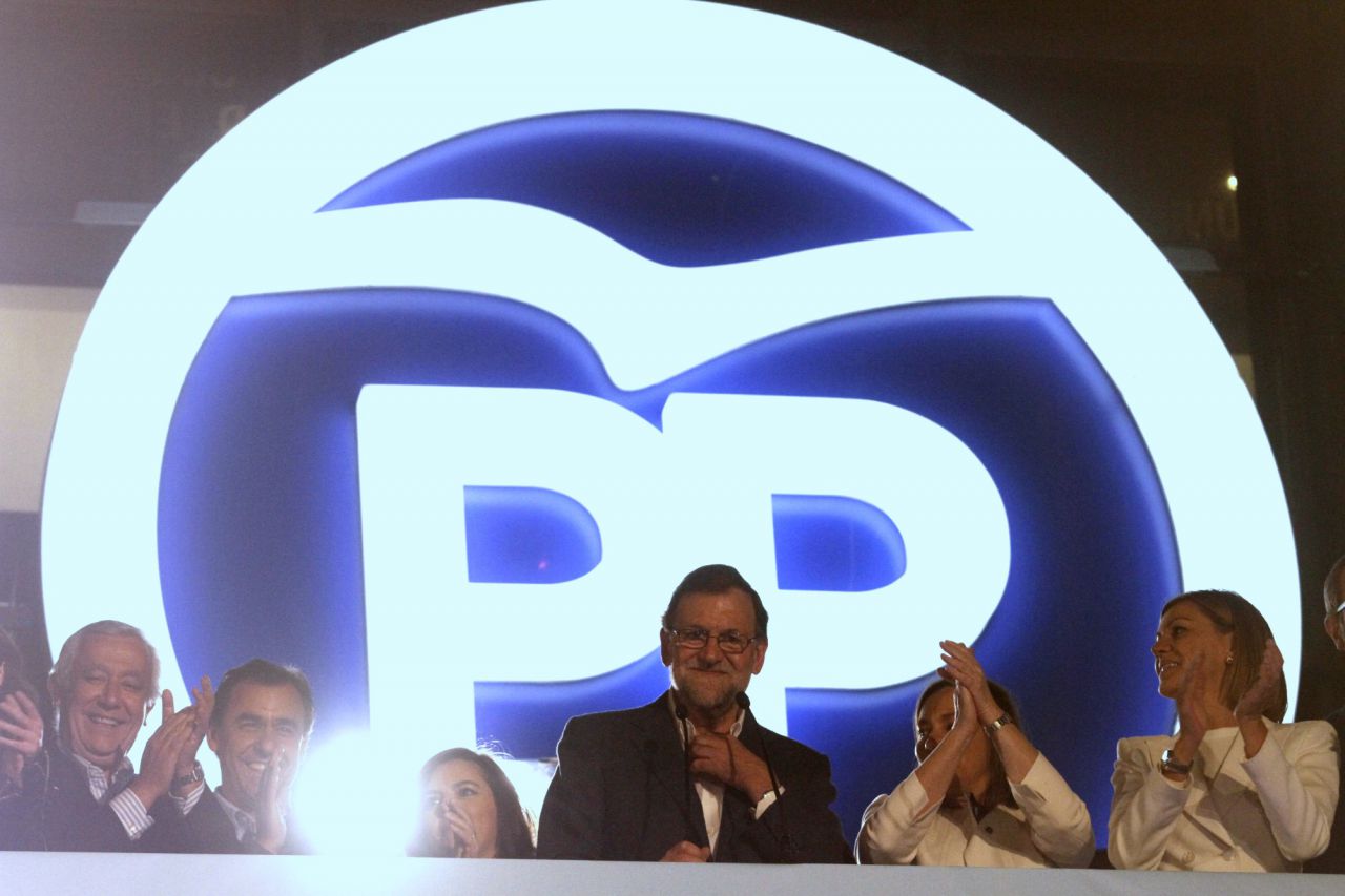 Rajoy, junto a miembros de su partido, saluda desde el balcón de su sede en Génova