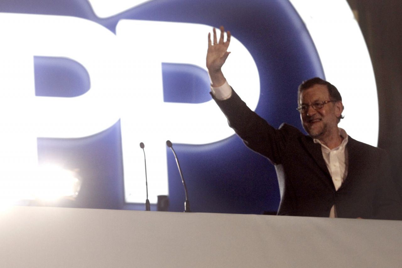 Rajoy, junto a miembros de su partido, saluda desde el balcón de su sede en Génova