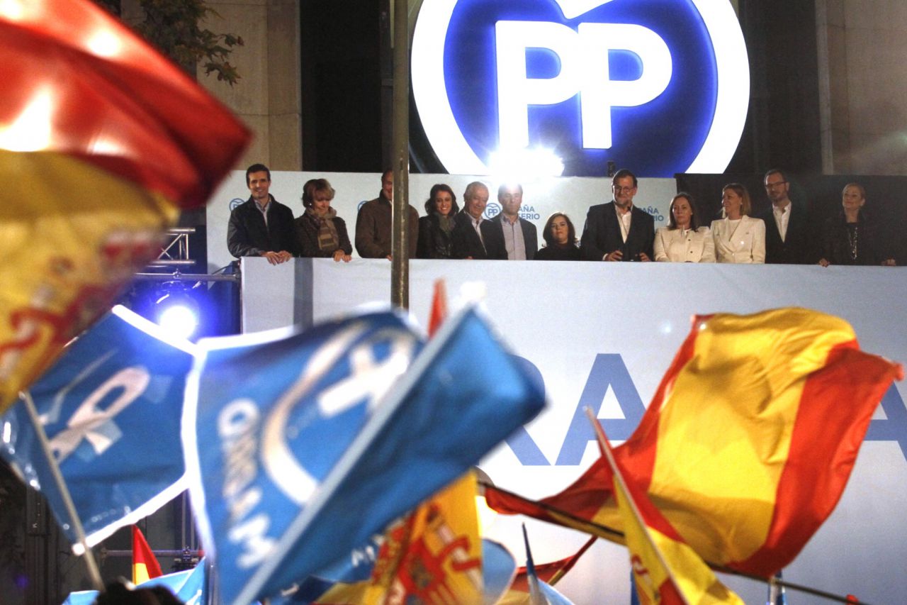 Rajoy, junto a miembros de su partido, saluda desde el balcón de su sede en Génova