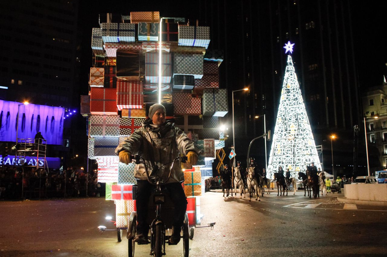 Tras los Reyes Magos, un paje real lleva muchos regalos en una bicicleta.