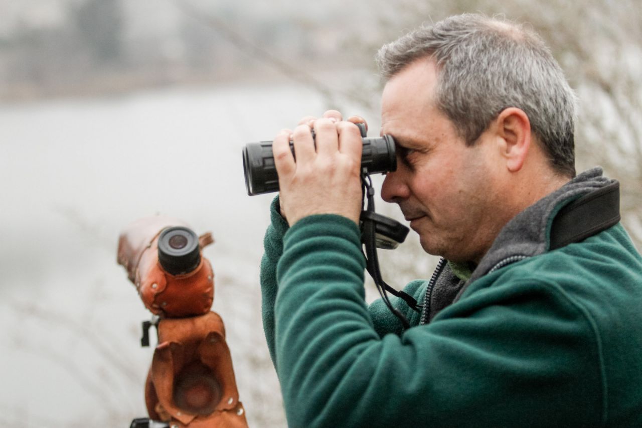 Un ornitólogo de Seo Bird Life observa aves con un prismático.