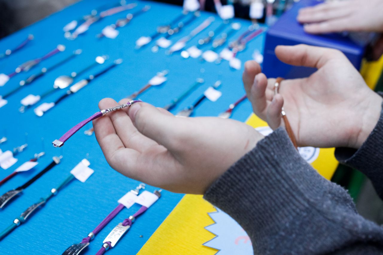 Un alumno enseña las pulseras realizadas a una potencial compradora.