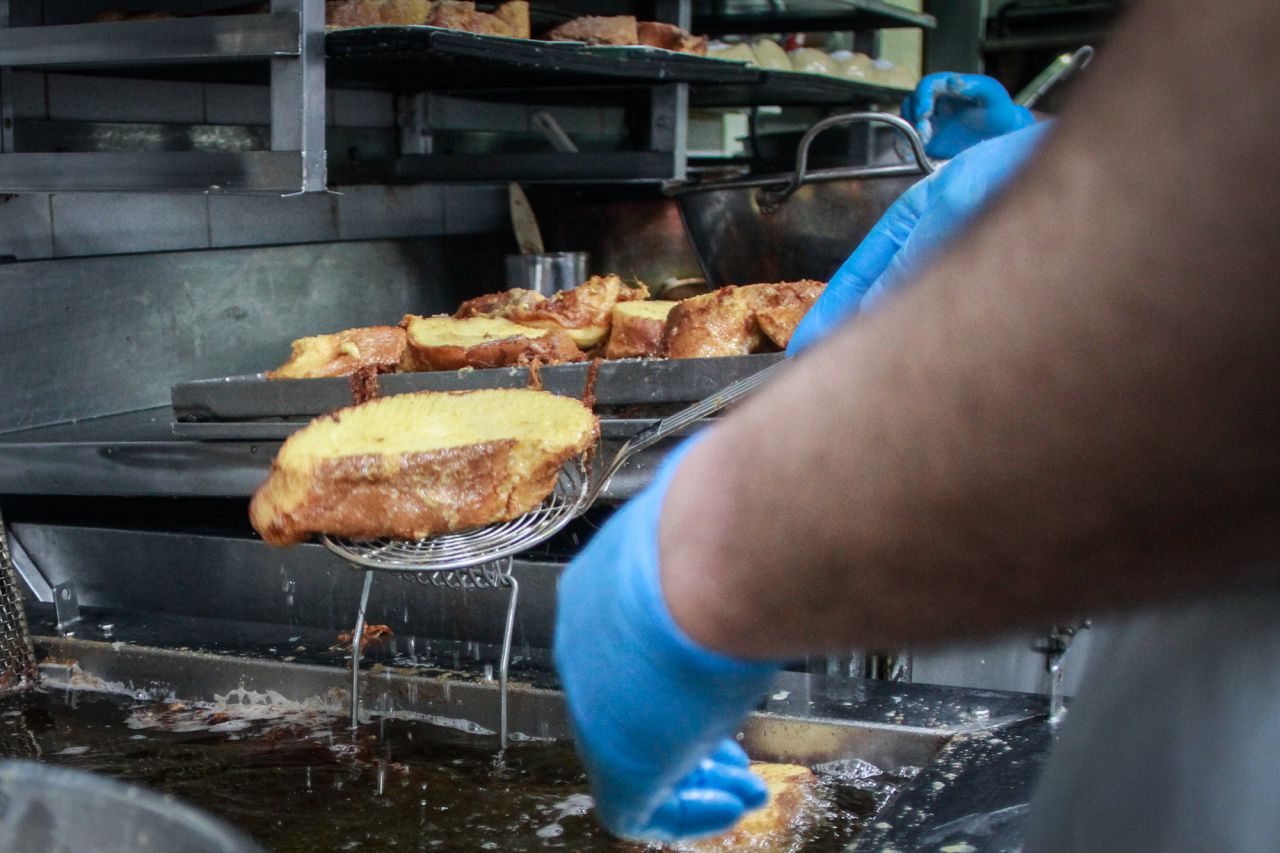Un operario del obrador de la Mallorquina escurre las torrijas una vez fritas.
