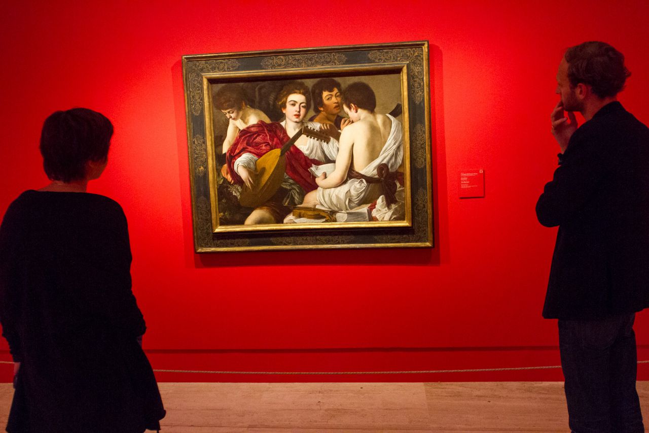 Dos personas observan 'Los músicos' de Caravaggio