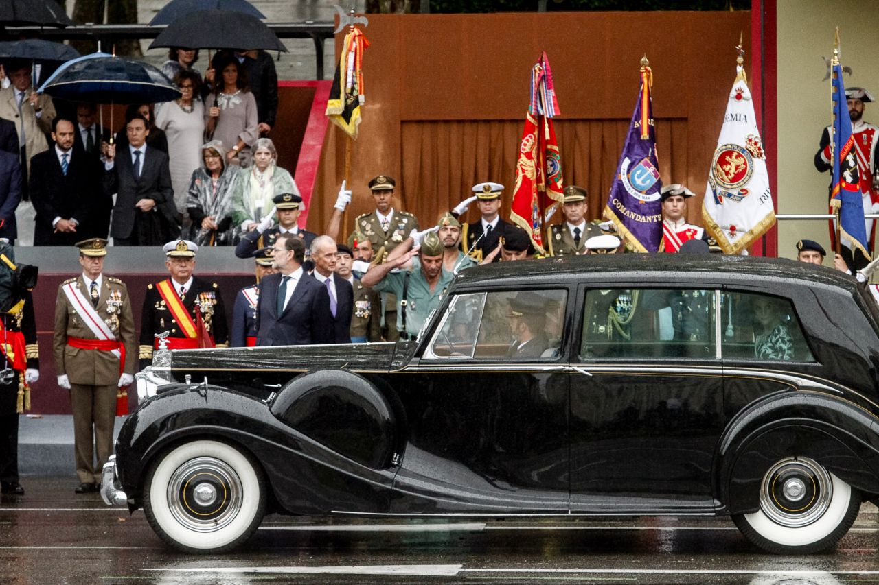 Sus Majestades los Reyes abandonan la plaza de Cánovas del Castillo tras la finalización del desfile.