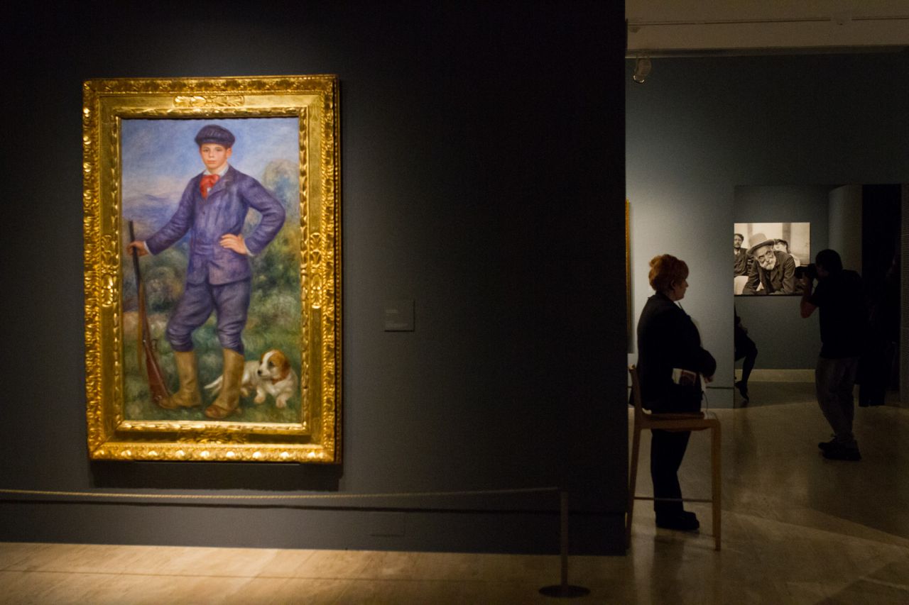 Jean como cazador   1910 Óleo sobre lienzo. 172,7 × 88,9 cm Los Ángeles, Los Angeles County Museum of Art.  Donación debida a la generosidad del difunto  Sr. Jean Renoir y la Sra. Dido Renoir. Al fondo fotografía de Pierre Auguste Renoir.