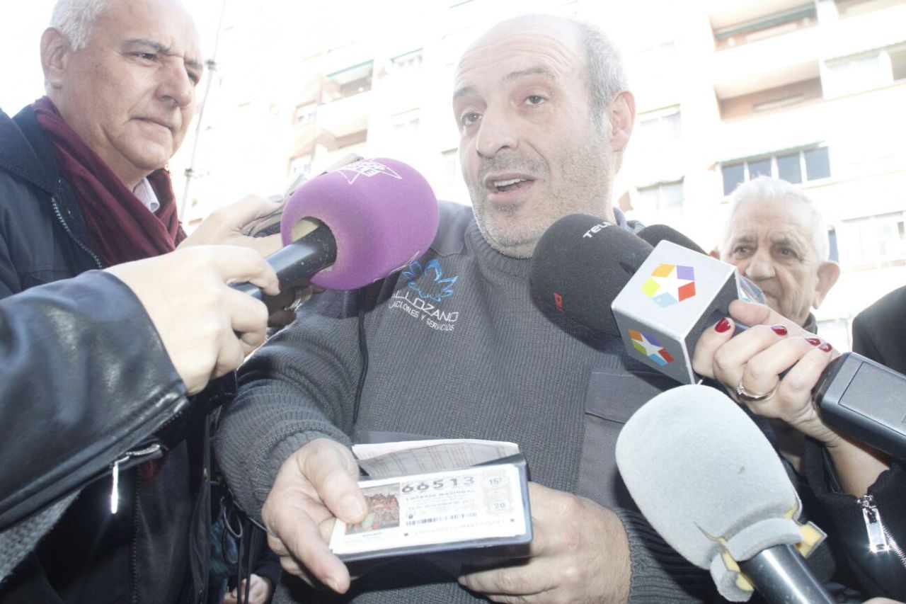 Uno de los ganadores de 'El Gordo' de Navidad sujeta su boleto premiado en el madrileño Paseo de la Esperanza.