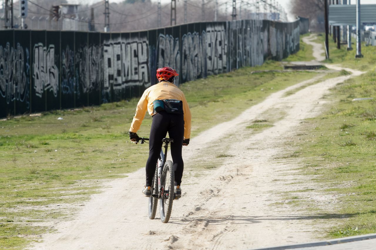 Un ciclista transita por el camino que discurre de forma paralela a las vias del tren de Cercanías de la línea C5. 