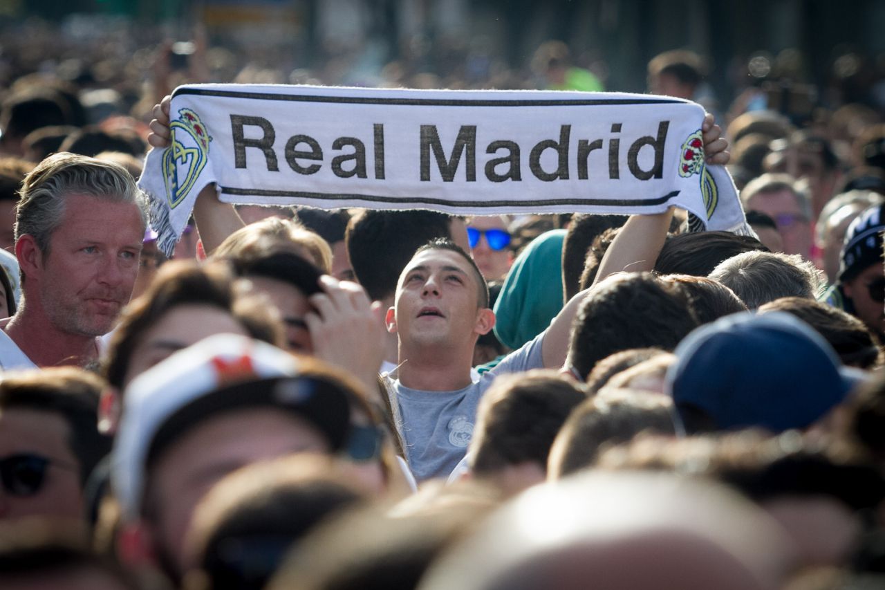Aficionados del Real Madrid aguardan la llegada del autobús del equipo.