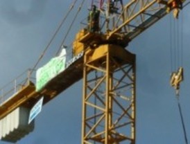Reclama un pago subido a una grúa