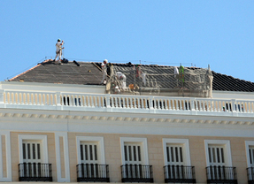 Sobre los tejados de los edificios los obreros desmontan el cartelon luminoso de Firestone tras Escuelas Aguirre y montan en el de Sol el de Apple