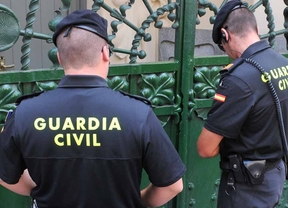 Pareja de Guardia Civiles intentando abrir una reja de espaldas