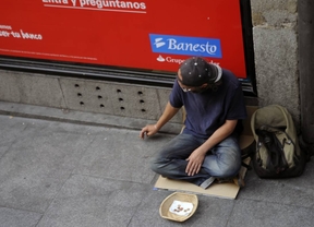 Un hombre pobre y sin trabajo mendiga ante un banco en la calle Mayor