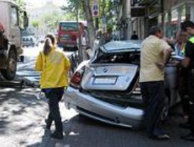Una grúa arrastra a un coche, con su conductora, hasta empotrarlo a una farmacia