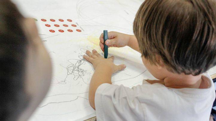 Un niño pinta en la mesa en la clase de educación infantil.