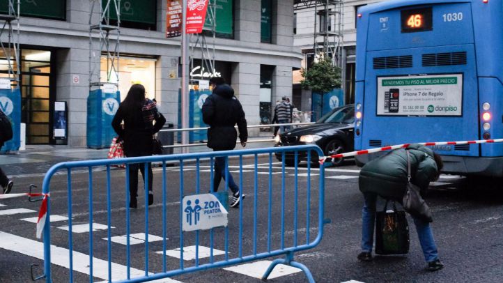 Peatones cruzan tras pasar una cinta de seguridad colocada en un cruce por el corte de la Gran Vía.