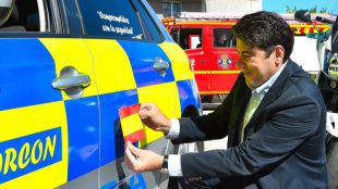 David Pérez pega una bandera española en un coche de la Policía Local